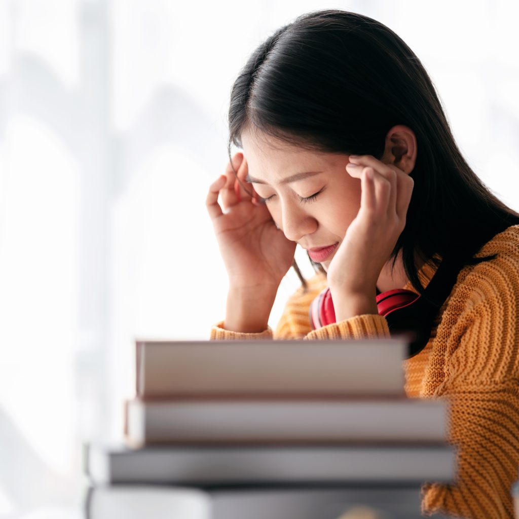 Student concentrating on study materials and managing exam stress with support from economic tuition
