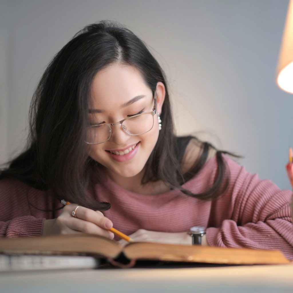 Student smiling while working through economics notes during economic tuition, showing growing confidence and engagement with the subject